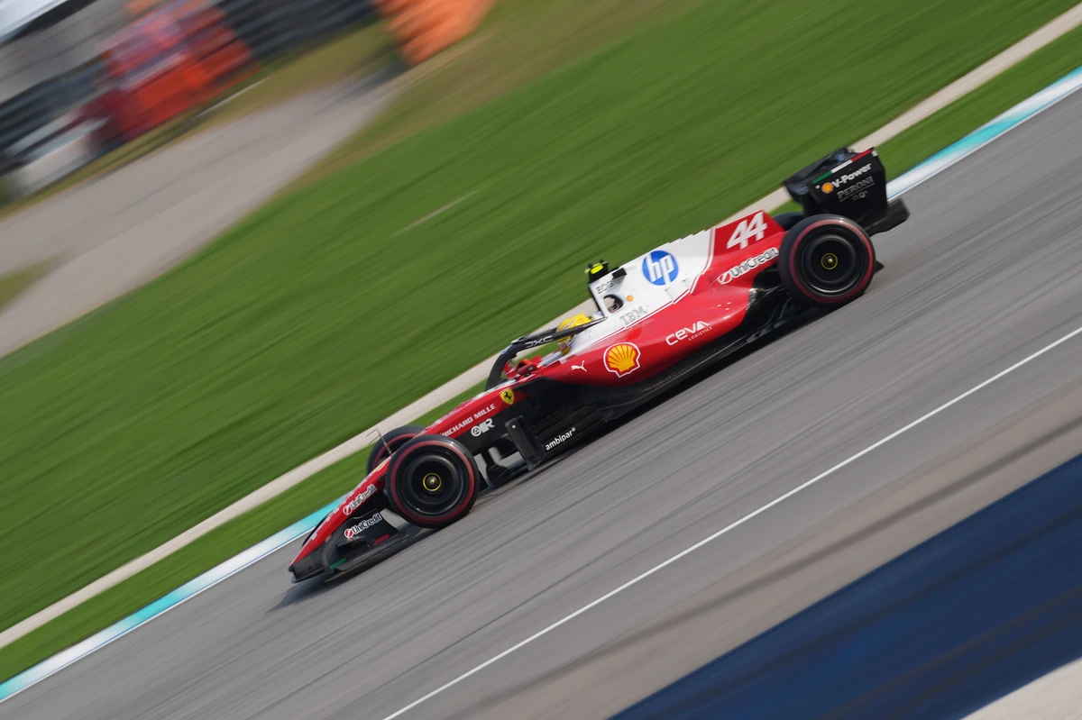 Red and white Ferrari number 44 crossing diagonally through a blurred Sepang Circuit