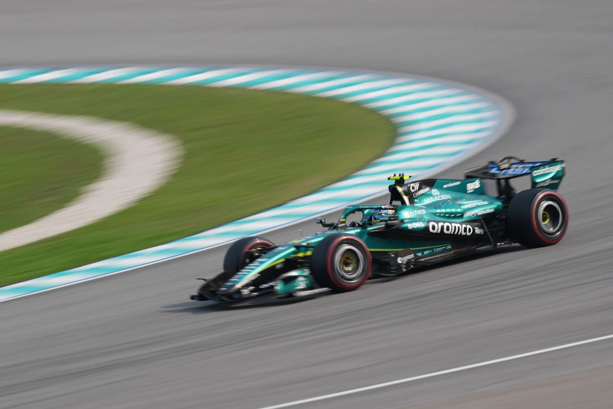 Panned Aston Martin with a curved turquoise kerb and blurred grass at Sepang Circuit
